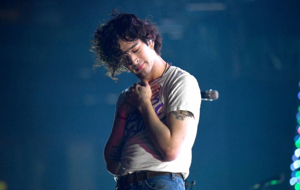 Watch The 1975’s Matty Healy return to stage in hospital gown following illness - www.nme.com