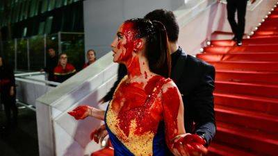 At Cannes, a Ukrainian Influencer Was Dragged Off the Red Carpet For Her (Fake) Bloody Protest - www.glamour.com - Britain - Ukraine - Russia